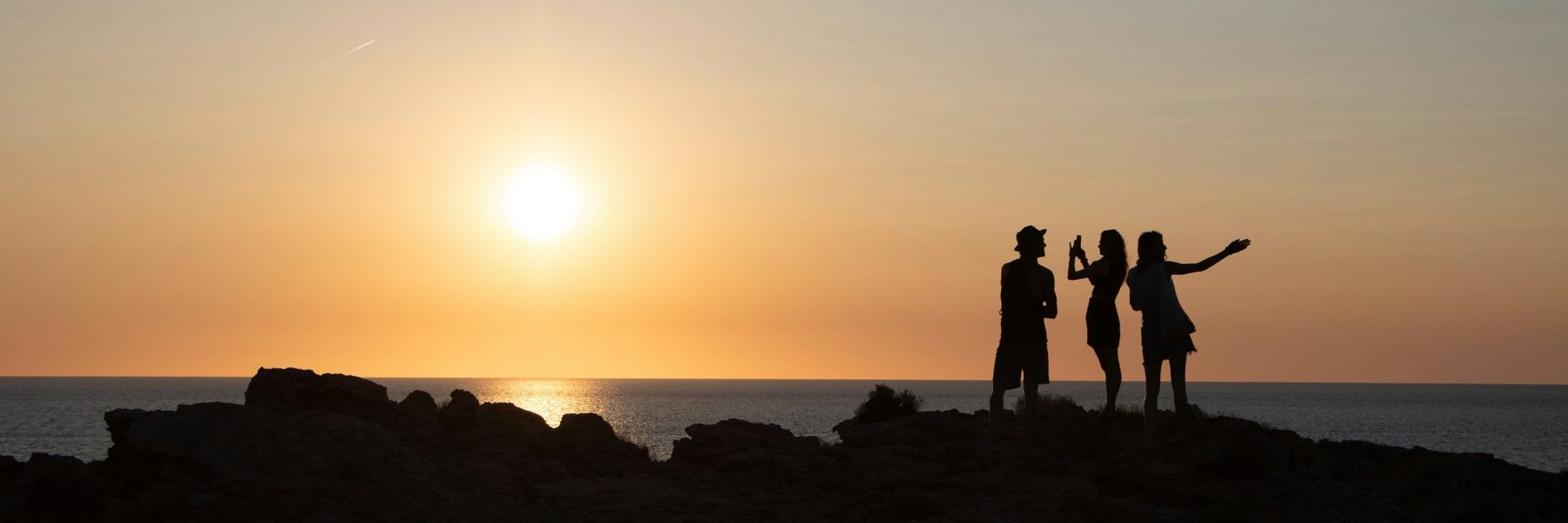 Three friends on the rocks at sunset, Ibiza